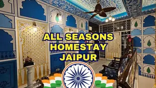 Vibrant blue room with ornate patterns, ceiling fan, and wall lamps. Text: "ALL SEASONS HOMESTAY JAIPUR" over Indian flag design.