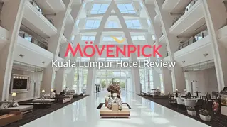 Modern hotel lobby with high ceilings, white decor, and seating areas. Text reads "Mövenpick Kuala Lumpur Hotel Review" in red and white.