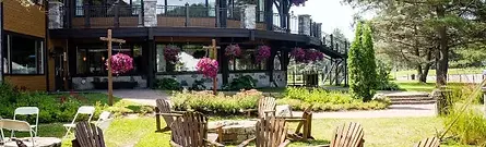 The scenic wooden exterior and relaxing outdoor patio seating at Manoir du Lac Delage near Quebec City, Canada.