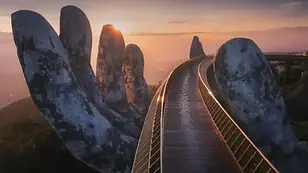Golden Bridge at Ba Na Hills with giant stone hands at sunrise near Da Nang.