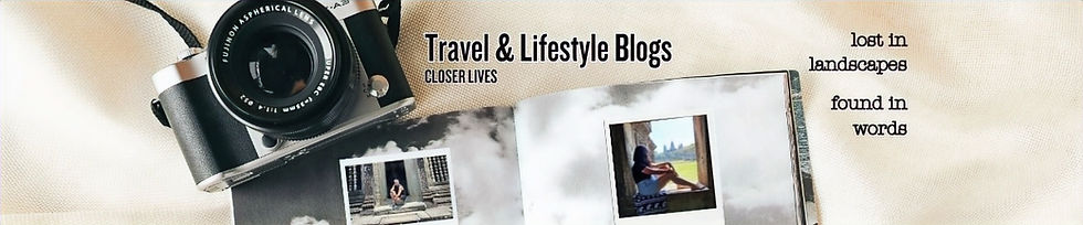 A camera and an open photo book with travel photos sit on a light fabric background. Text reads “Travel & Lifestyle Blogs, Closer Lives. Lost in landscapes, found in words.