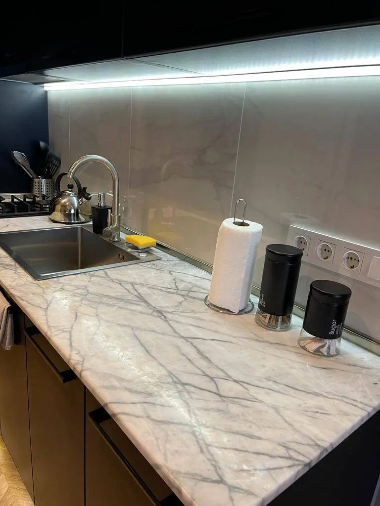 A marble worktop with a sink and several jars on it.