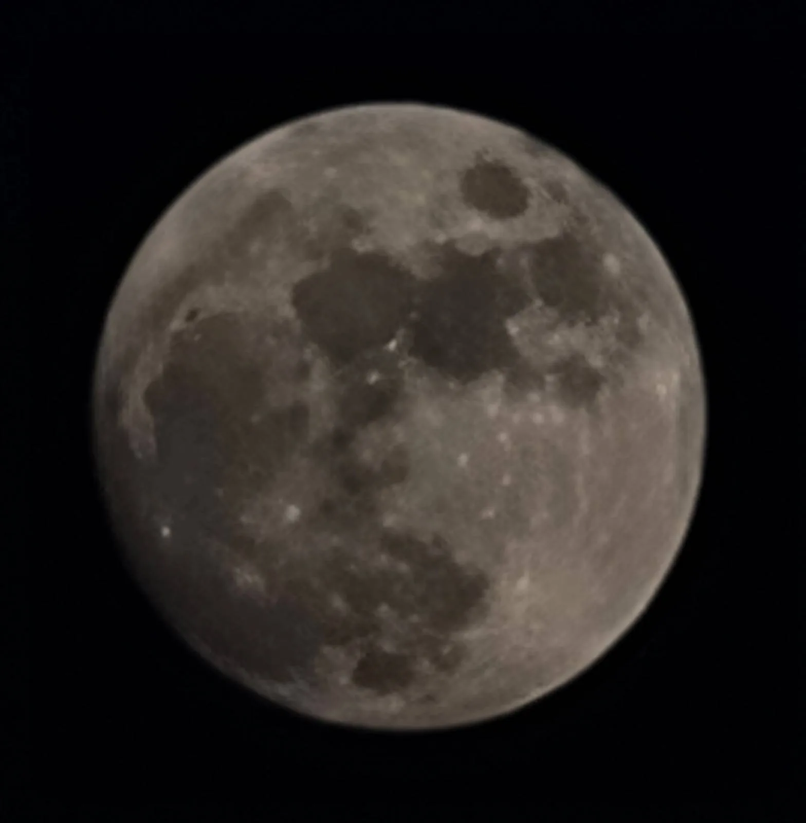 A detailed image of the full moon against a black night sky. The surface shows various shades of gray with visible craters and darker lunar maria, giving it a textured appearance.