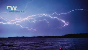 Lightning illuminates a dark, cloudy sky over a lake with silhouetted trees. Bold white "rw networks" text in the top left corner.