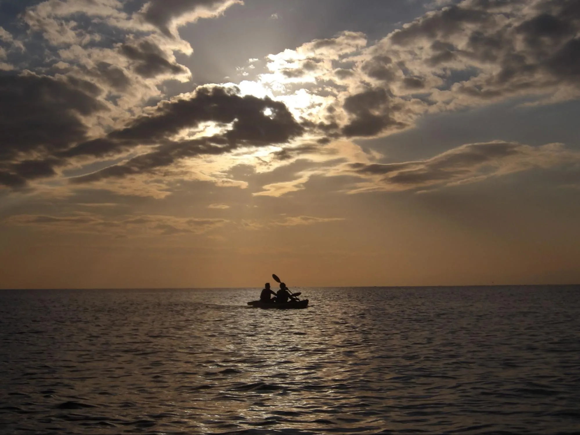 黃昏時分，海上有兩個人正划著獨木舟