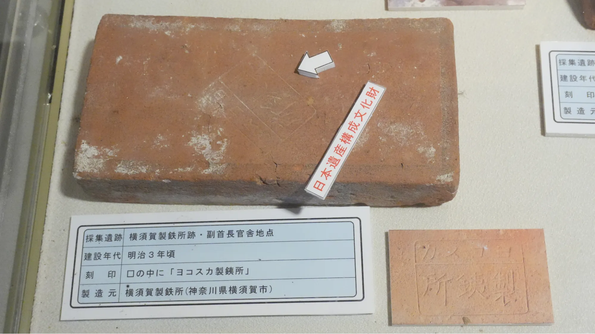 一塊被放置在玻璃櫃中的紅色磚頭，被標示為日本遺產文物