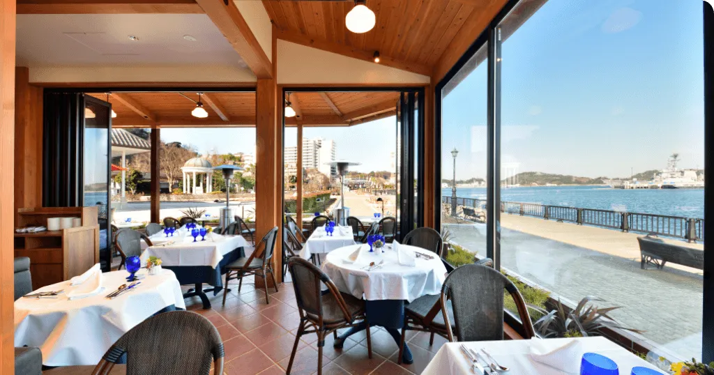 明亮的餐廳擺放多張用餐桌椅，窗外可以欣賞到海景