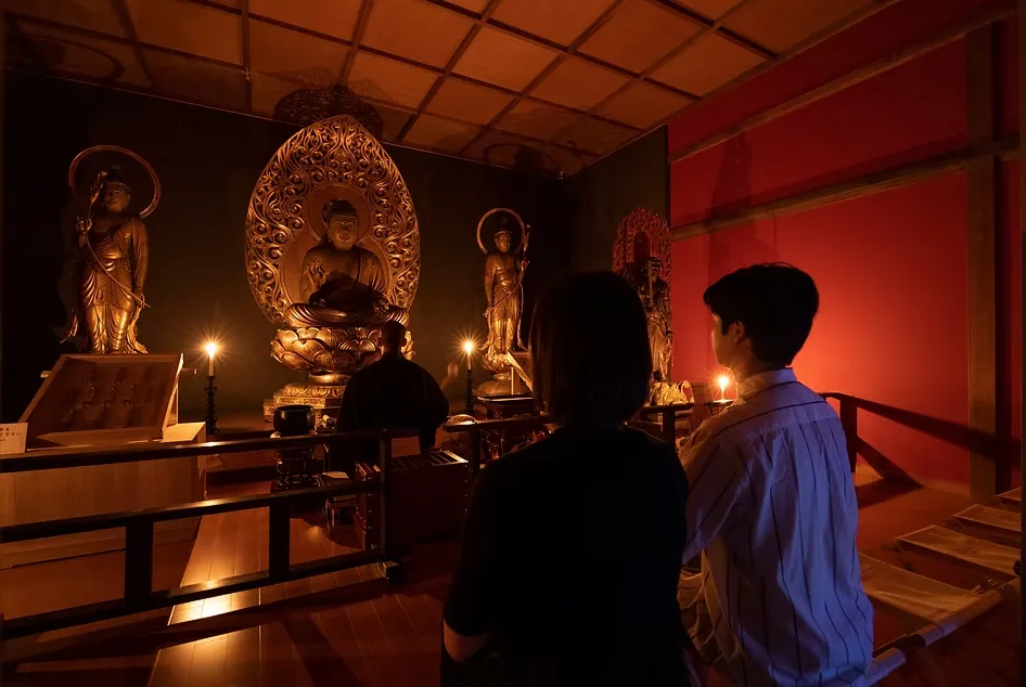 兩位信眾跟著法師在燭光中祭拜神像