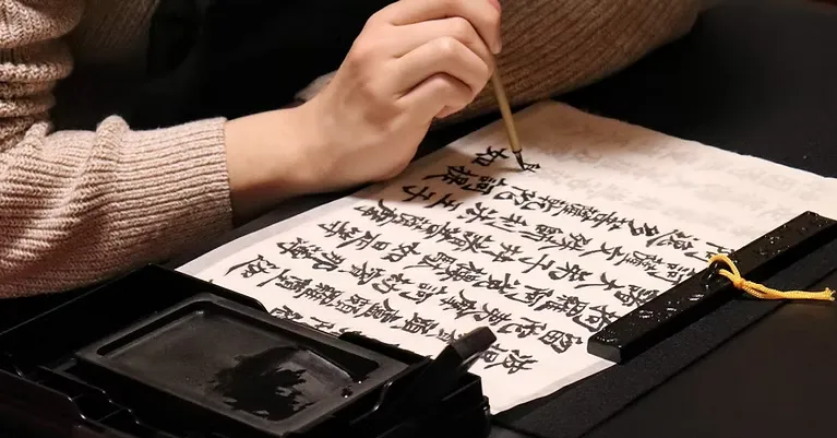 一個人正拿著毛筆在書寫經文