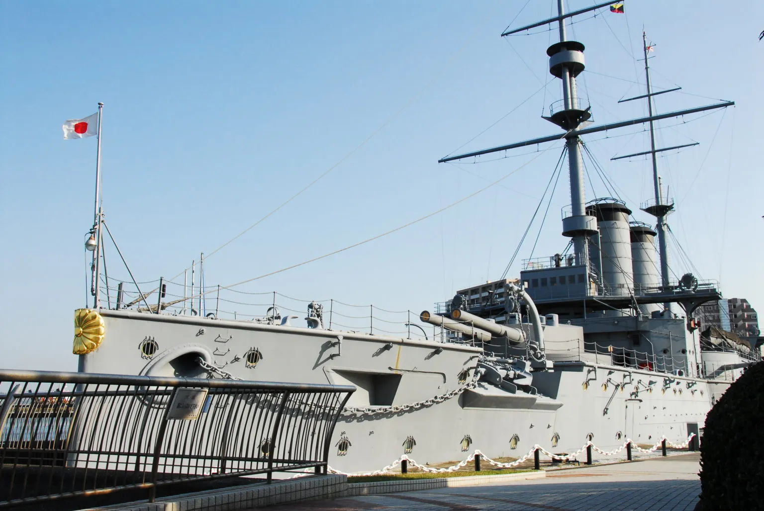 灰色軍艦三笠號停靠在港邊，並插有日本國旗