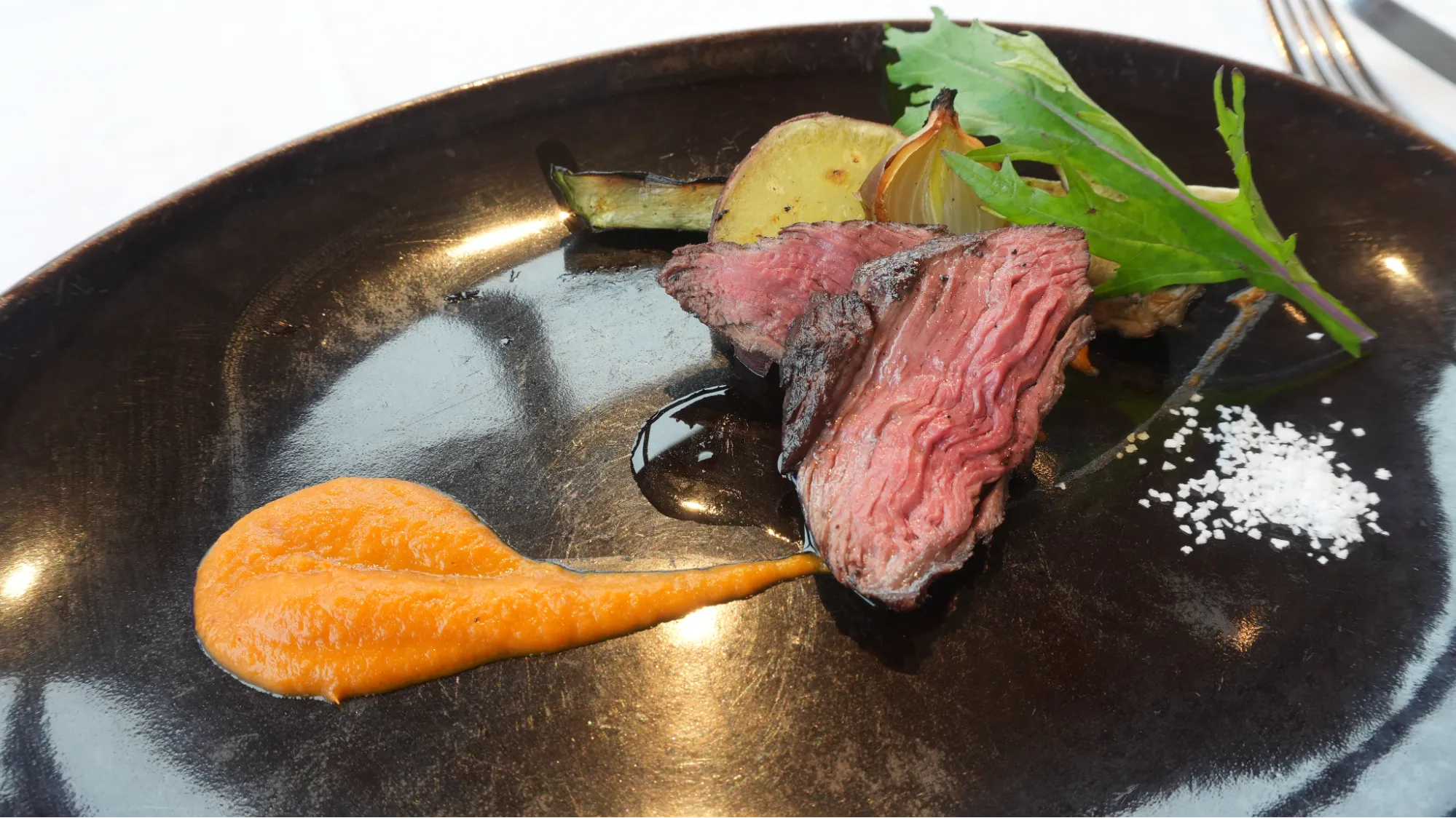 一份主菜紅肉和配菜擺放在黑色盤子