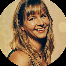 A smiling white woman with long blonde hair on a gold background.