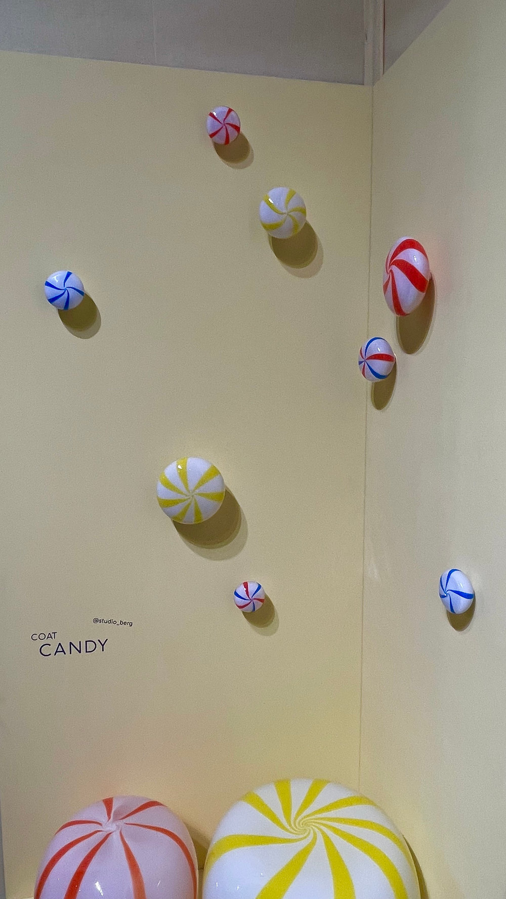 coatCANDY glass hooks on the yellow wall of the STUDIO BERG stand, with CANDY side tables