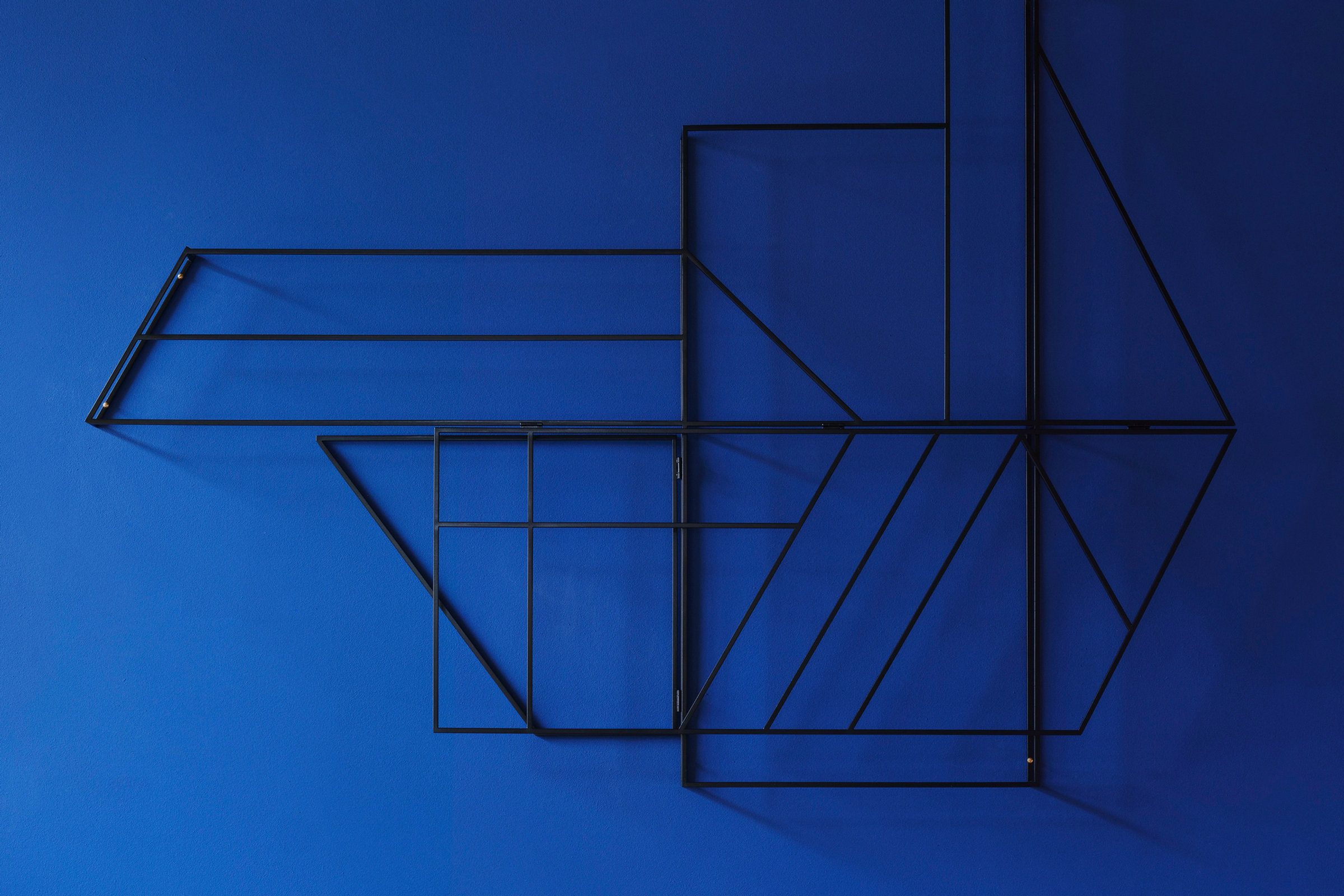 FOLDWORK wall object by STUDIO BERG in powder-coated steel on a blue wall