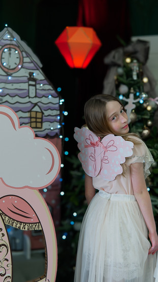 ילדה בתחפושת פיה עם כנפיים ורודות עומדת ליד כרכרה