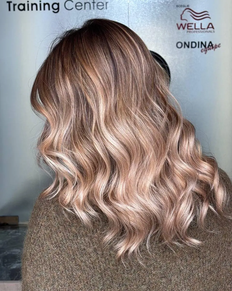Capelli mossi con balayage color caramello caldo realizzato presso il salone Nujé Parrucchieri, Udine. Riflessi dorati effetto baciata dal sole ideali per basi castane.