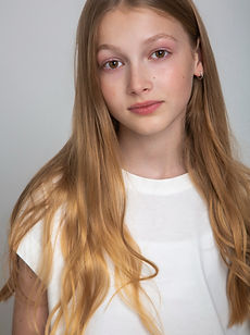 Bella - a headshot of a junior model with long hair, a natural smile, and wearing a white t-shirt with a cherry image, represented by ROC Talent Agency UK