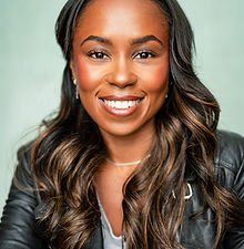 Kerry - headshot of a female presenter with long curly hair, a bright smile, and wearing a shirt under a grey jumper, represented by ROC Talent Agency UK