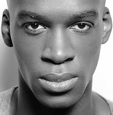 Michael B - black and white headshot of a male presenter with an intense look, a clean shaven face, and wearing a T-shirt, represented by ROC Talent Agency UK