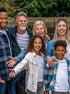 The Nugent Family - a family modelling shot with two parents, two grandparents, all with bright natural smiles and expressions. Accompanied by their two children, their daughter with long dark curly hair and their son with a wide smile and short curly hair, all together outside, represented by ROC Talent Agency UK
