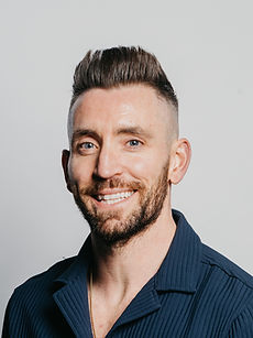 Ryan - headshot of a male presenter with swept back brown hair, a trimmed beard, and a wide smile, represented by ROC Talent Agency UK
