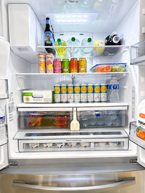 Brightly organized refrigerator stocked with High Noon seltzers, Angry Orchard ciders, Bloom sparkling beverages, bottled water, fresh fruit, yogurt, and snacks as part of a Scottsdale bachelorette fridge stocking service.