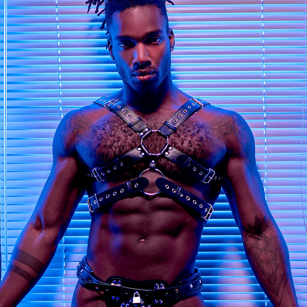 male model wearing a black pu leather harness against a blue background