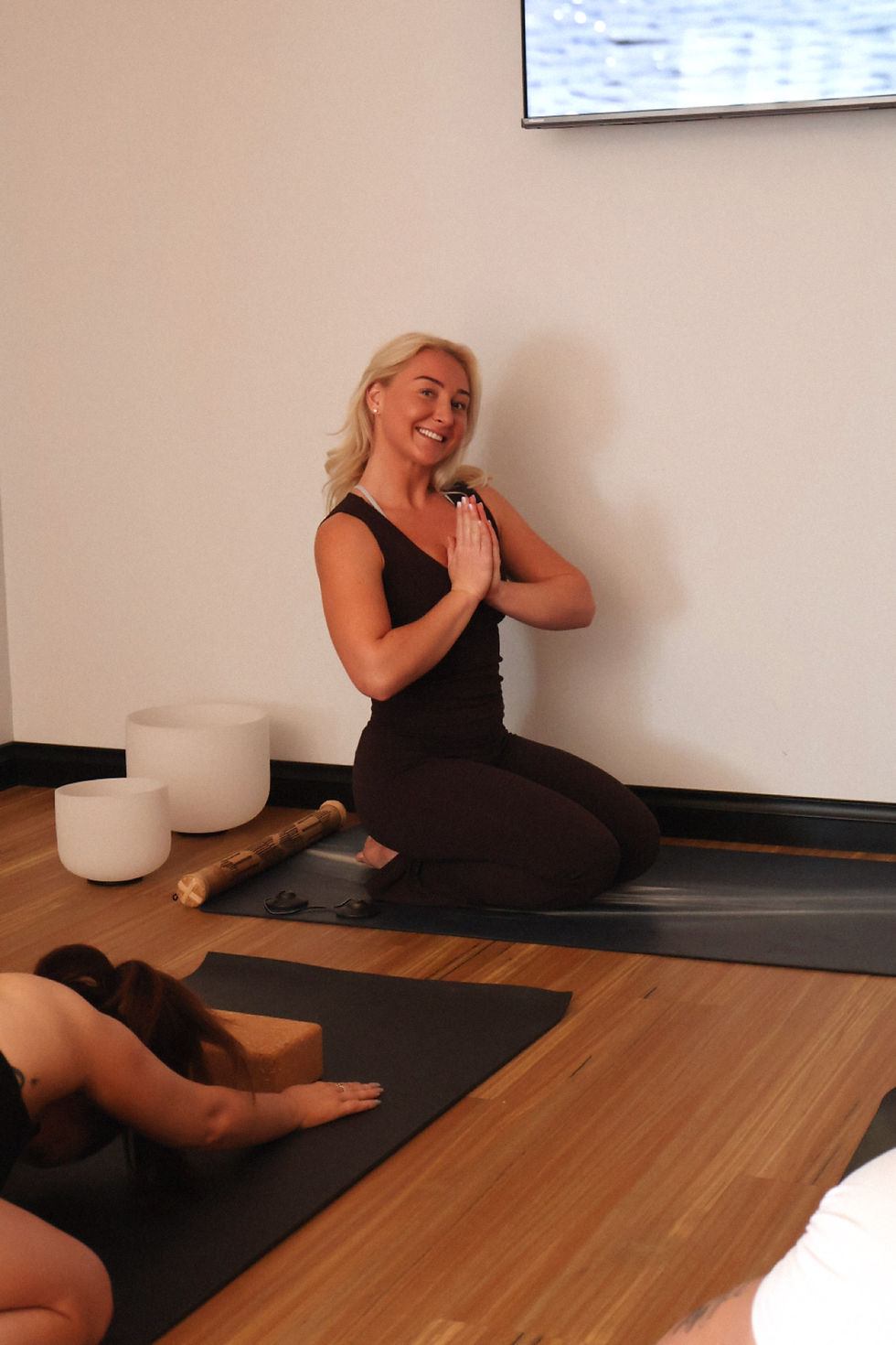 Nicole leading an outdoor vinyasa flow or sound healing session by the beach, emphasizing community and movement.