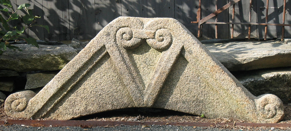 18th‑century French granite pediment with classical triangular profile in a garden setting.
