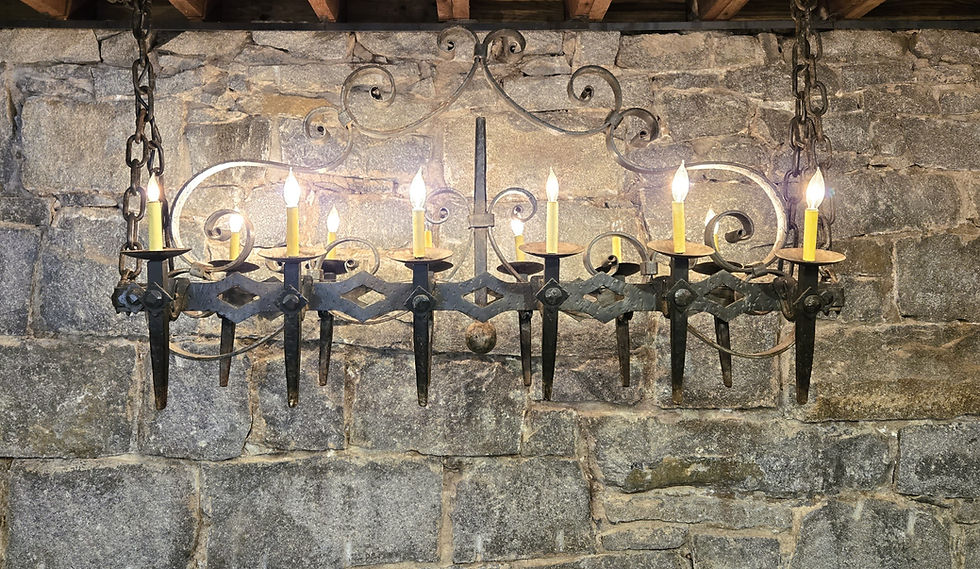 Black iron, medieval looking hanging light fixture with electric candles against granite wall