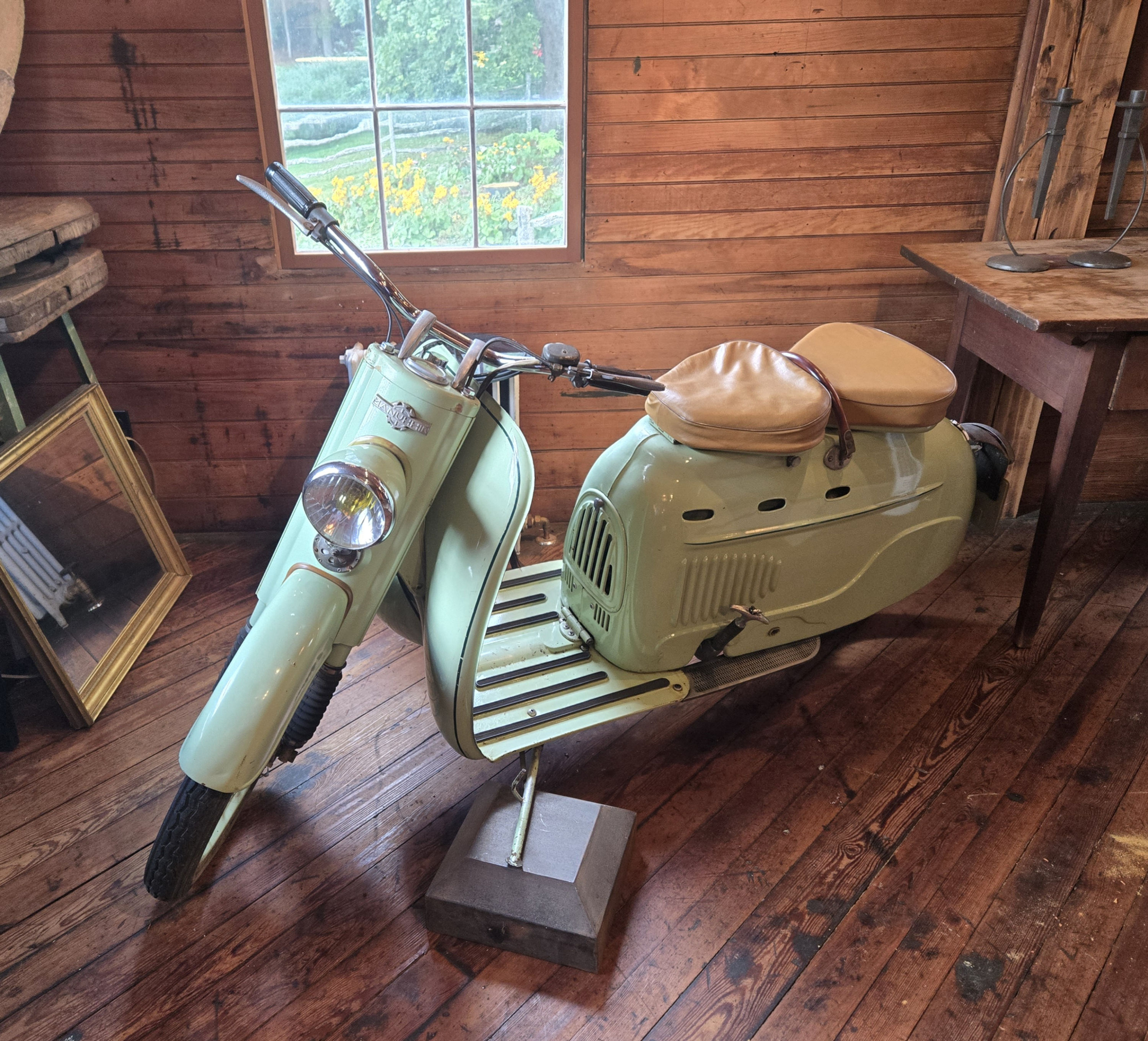 side view of Manurhin SM75 pastel green scooter with double seat in wooden building