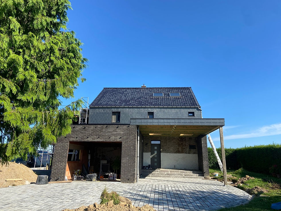 Maison en rénovation avec toiture en tuiles anthracite posée sur versants inclinés, bardage en ardoises artificielles et écha