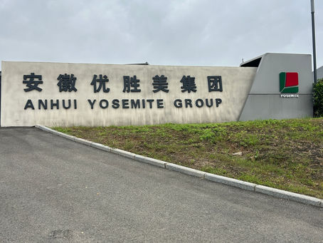 Entrance sign for Anhui Yosemite Group with Chinese and English text, beside a road and grass under a cloudy sky.
