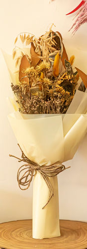 Dried sunflowers, wheat stalks, and golden thistles wrapped in cream parchment paper and tied with twine by SKfleur.
