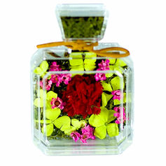 Close-up of a completed SKfleur DIY Blooms in a Bottle arrangement, showing a preserved flower centerpiece anchored into a natural moss base inside a square bottle