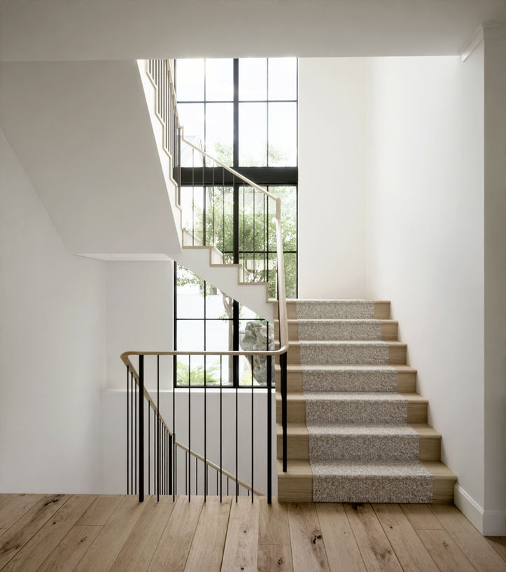 Minimalist stairwell with light wood treads and large vertical window for natural light
