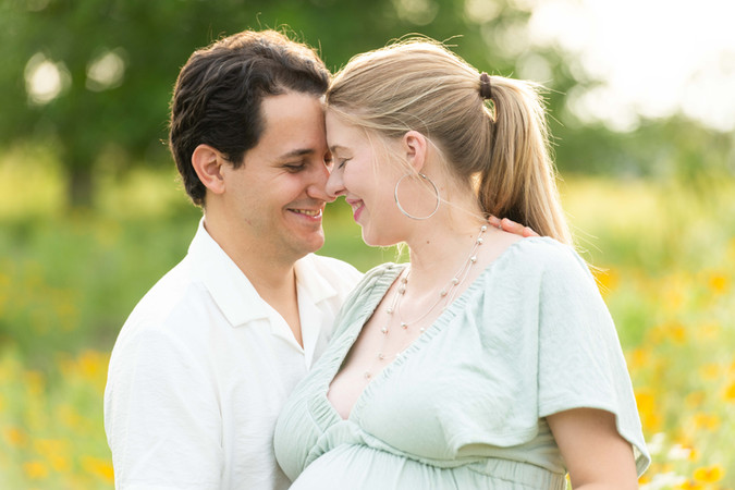 Dreamy flower field maternity photos Charlotte NC.  Couple standing in yellow flower field at North Carolina Museum of Art.
