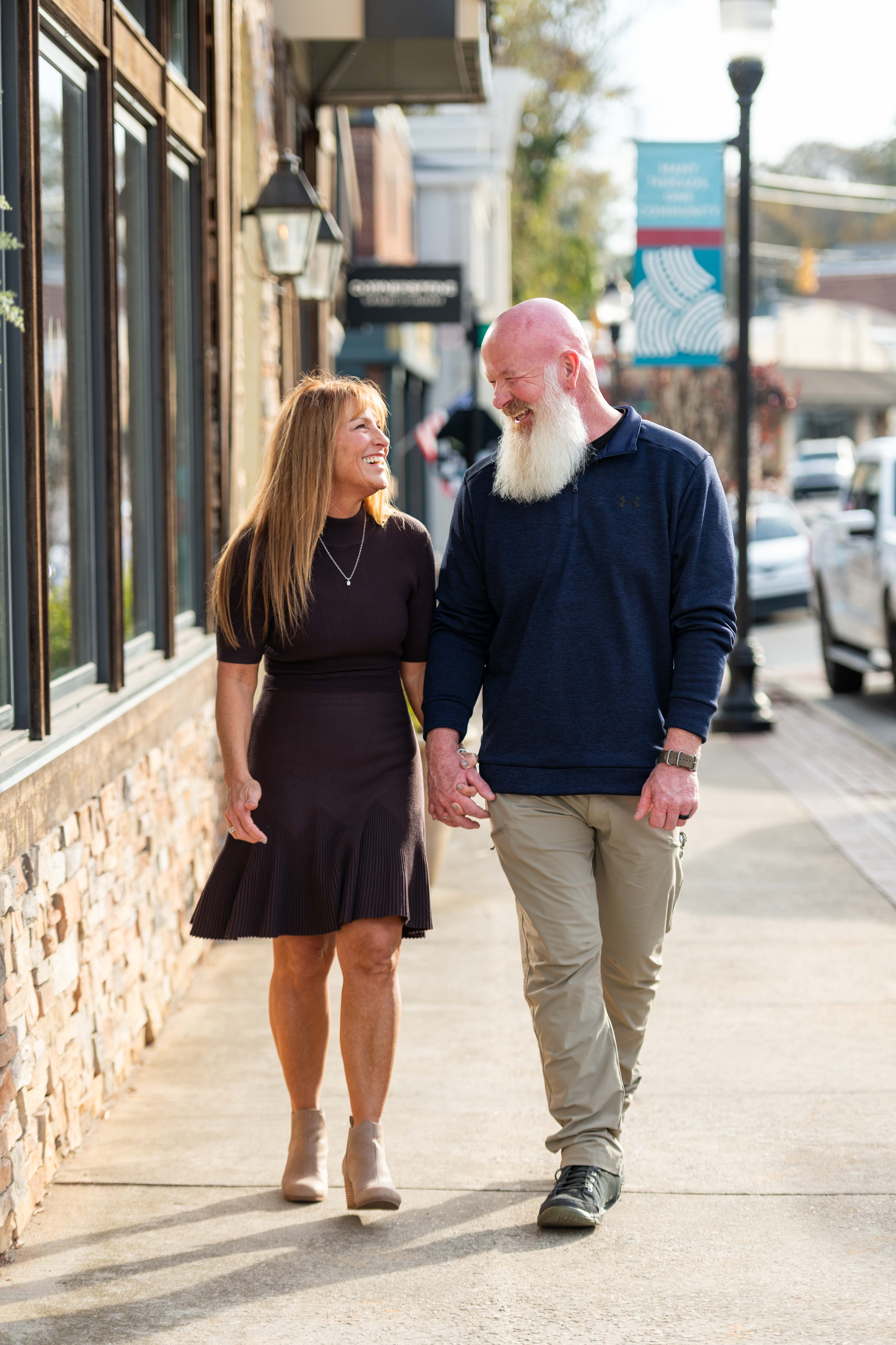 Photo of husband and wife walking down main street in Downtown Belmont, NC.  Family portrait photographers. 