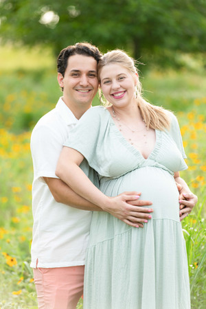 Dreamy flower field maternity photos Charlotte NC.  Couple standing in yellow flower field at North Carolina Museum of Art.