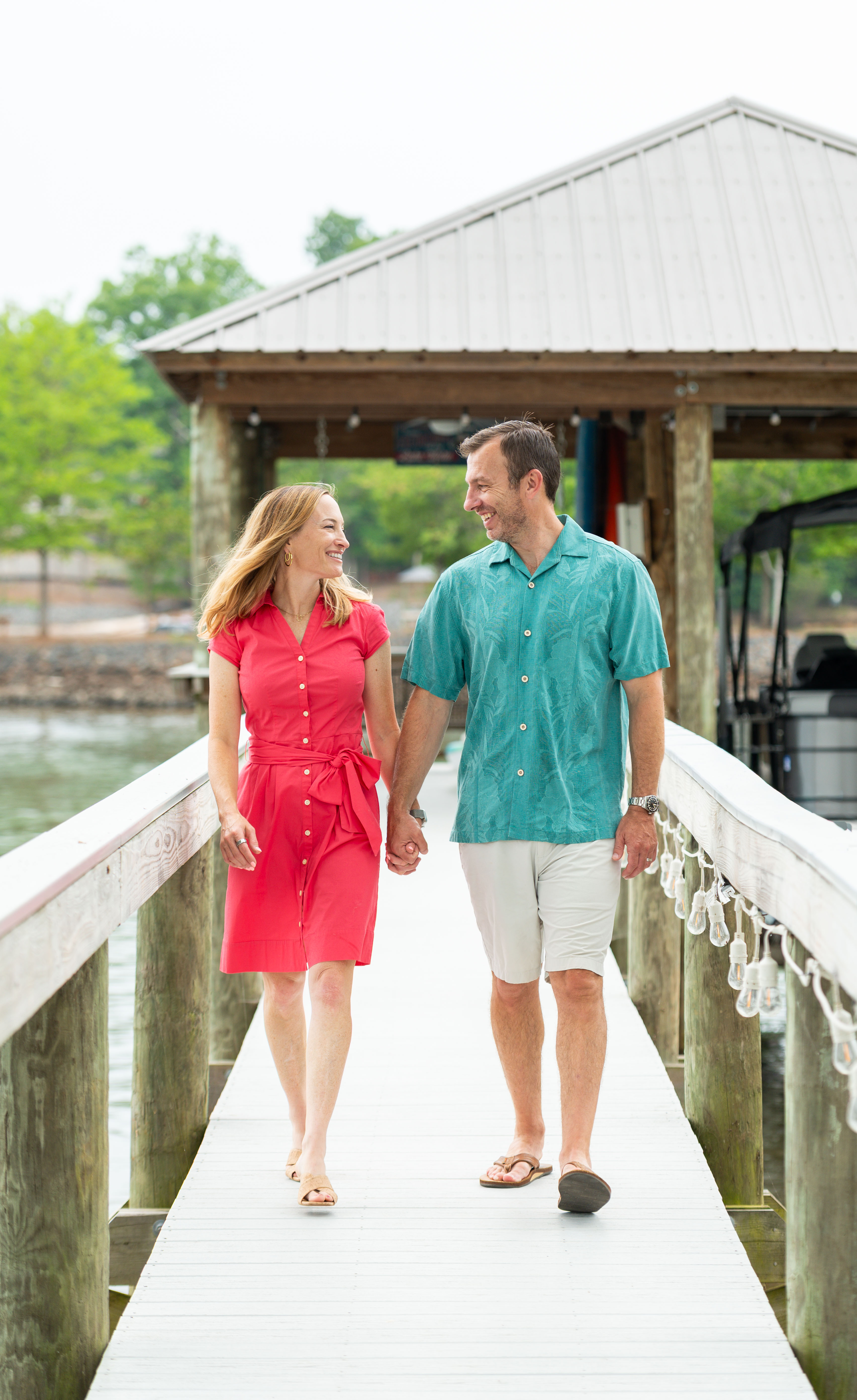 Romantic photo of a Mom and Dad walking on a dock on Lake Wylie in Belmont, NC.  Family photographers in Belmont, NC. 