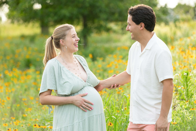 Dreamy flower field maternity photos Charlotte NC.  Couple standing in yellow flower field at North Carolina Museum of Art.