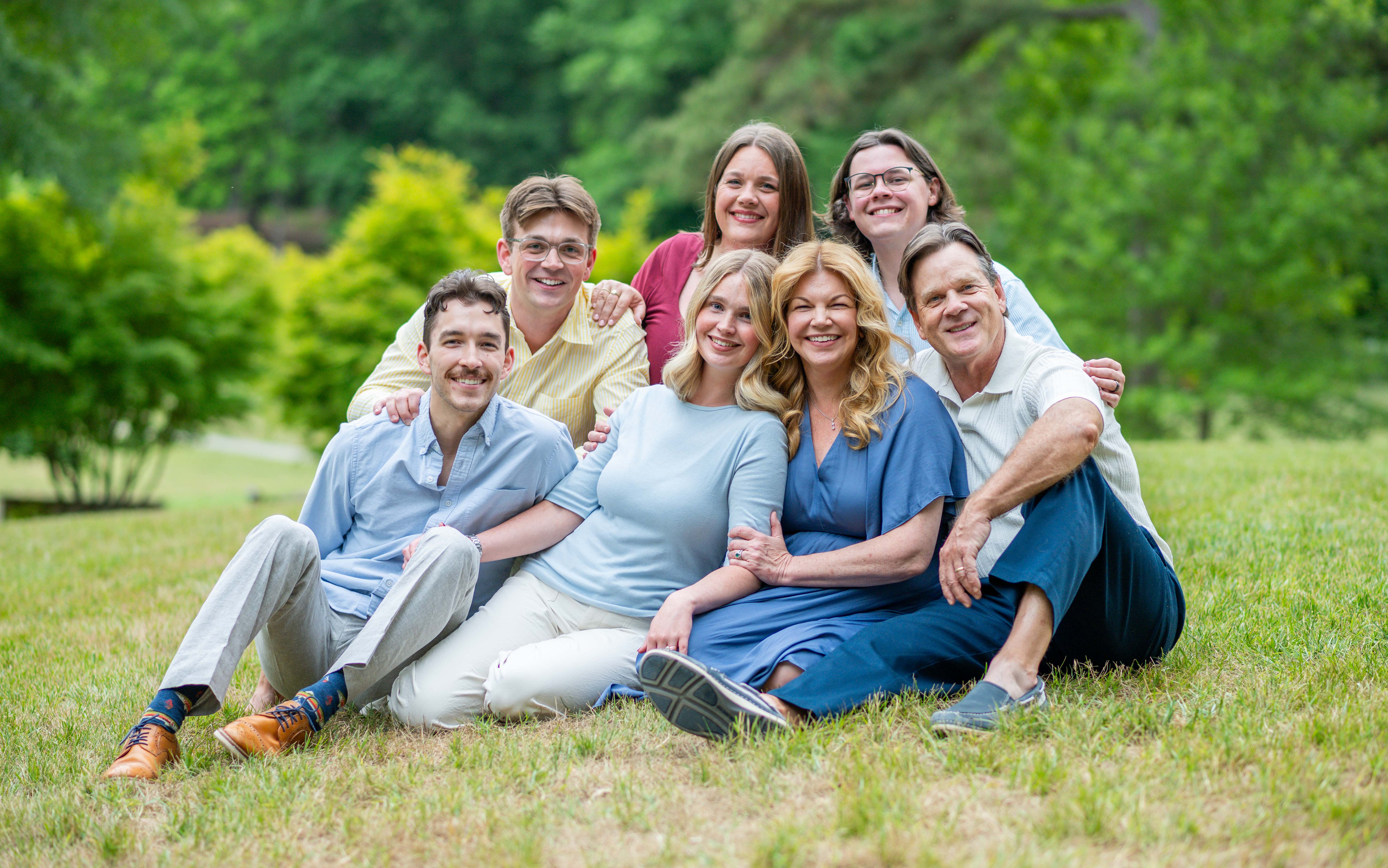 Candid photo of family sitting in grass cuddling together.  Extended family photography session in Charlotte, NC.  