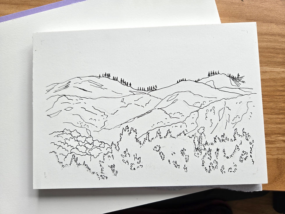 A pad of watercolor paper with a pen sketch of mountains with treetops in the foreground.