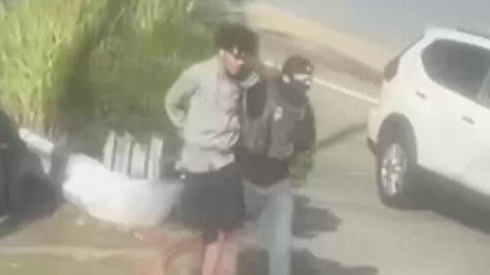 Vídeo mostra Gustavo algemado sendo conduzido por um agente do ICE mascarado