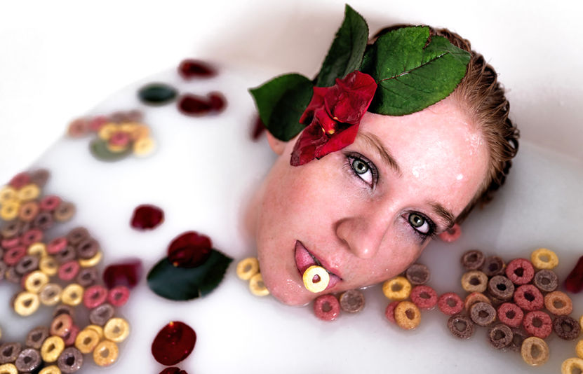 Kreatives Boudoir Shooting Frau im Milchbad beim Homeshooting mit Blumen und flakes in heller Umgebung