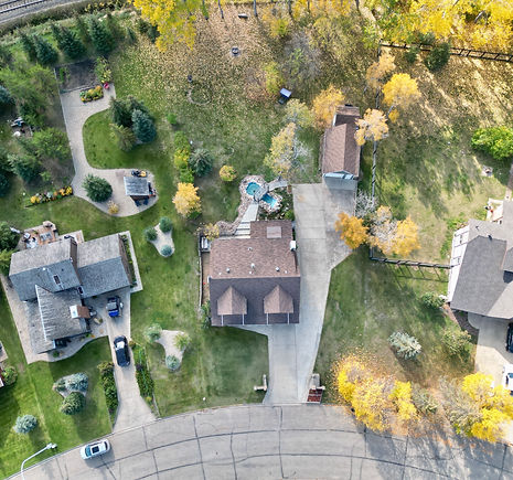 Aerial view capturing the autumn beauty of a house and its landscaped yard, adorned with colorful foliage.