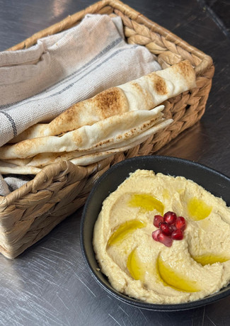 Hummus with olive oil and bread basket on table. Delicious dish concept.