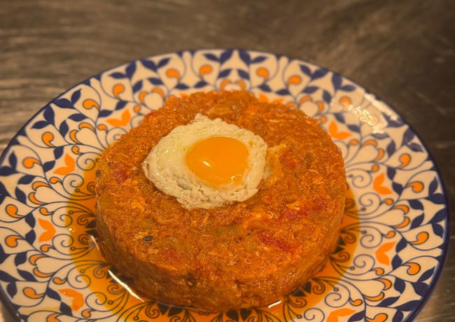 Ein Gericht mit Spiegelei. Orangefarbenes Essen auf einem Teller mit blauem Muster.