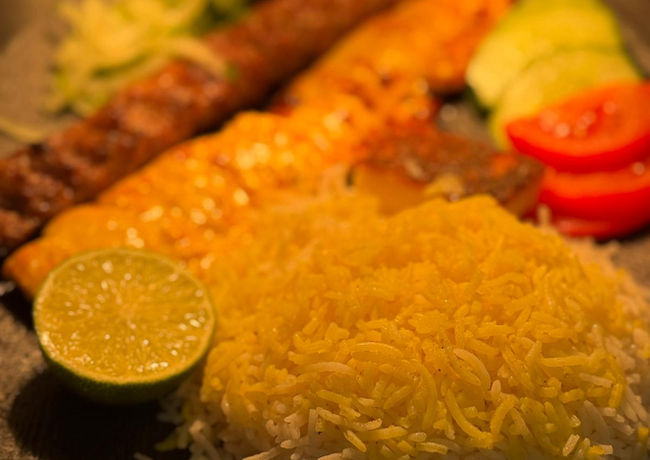 Gebratenes Fleisch auf einem Teller mit Reis, Gemüse und Zitrone serviert.