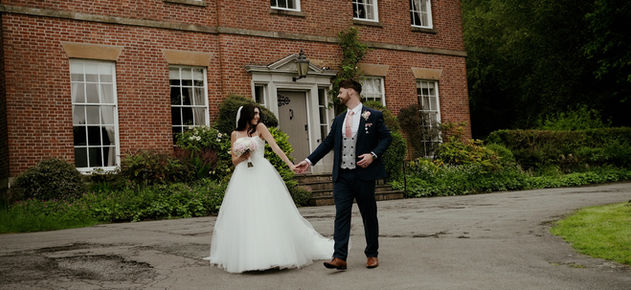Bride and groom walking outside the front of Rivington Barn after ceremony